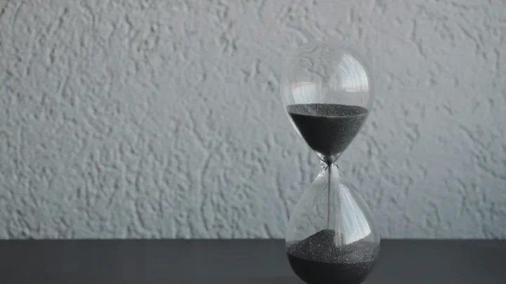 A clear glass hourglass with sand running through it