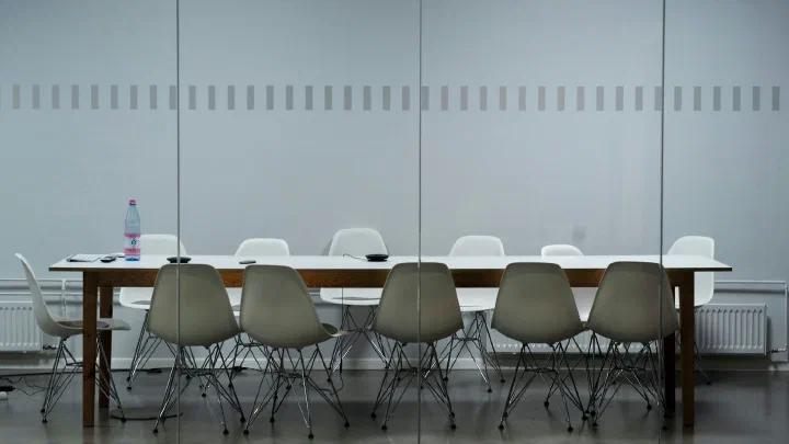 A long empty meeting table with chairs around it